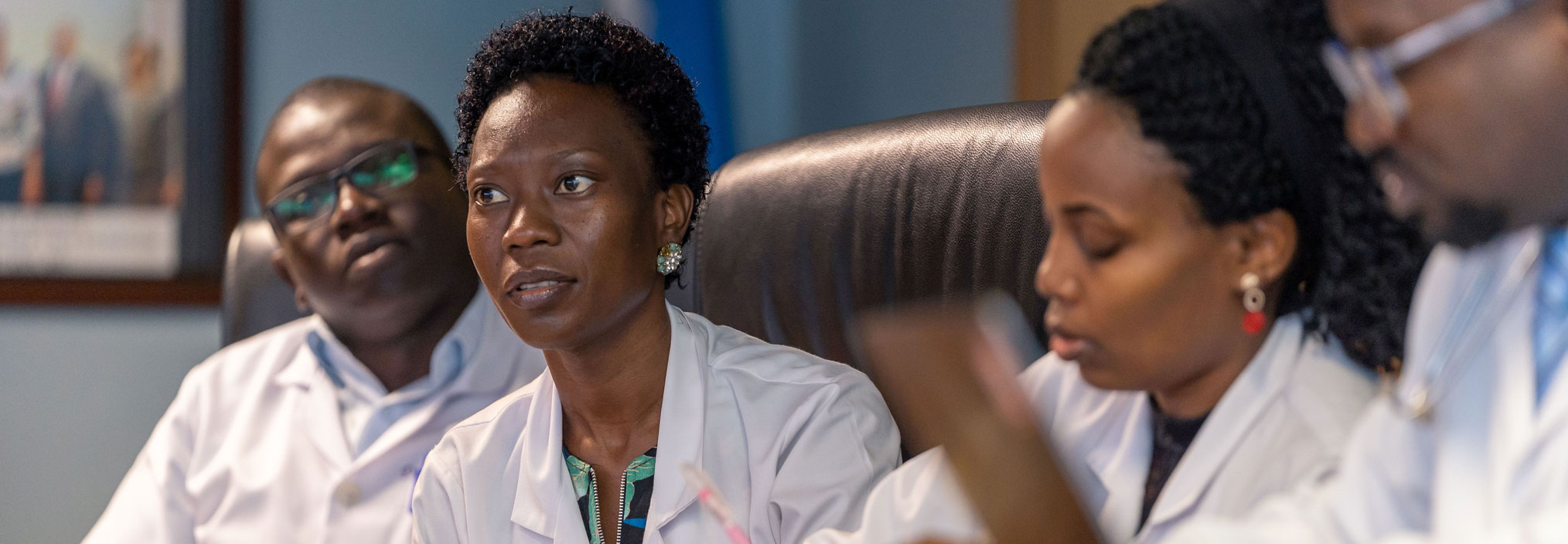 A group of four people in white lab coats engaged in a discussion.